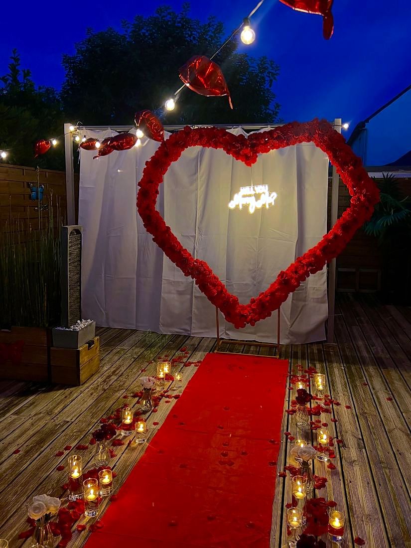 Cœur géant en roses rouges avec néon Will you marry me, tapis rouge et bougies